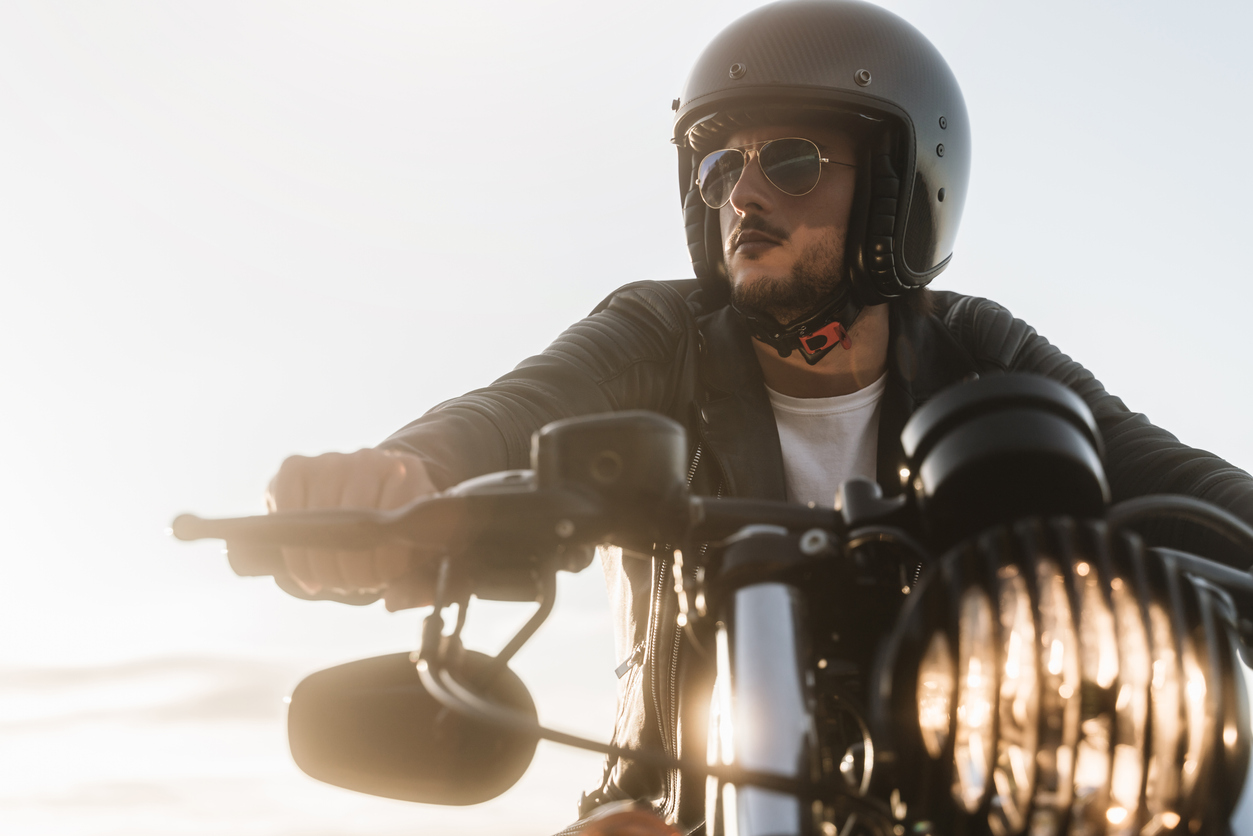 motorcycle rider in Kentucky looking away, sitting on his vintage motorcycle, wearing leather jacket, helmet and sunglasses