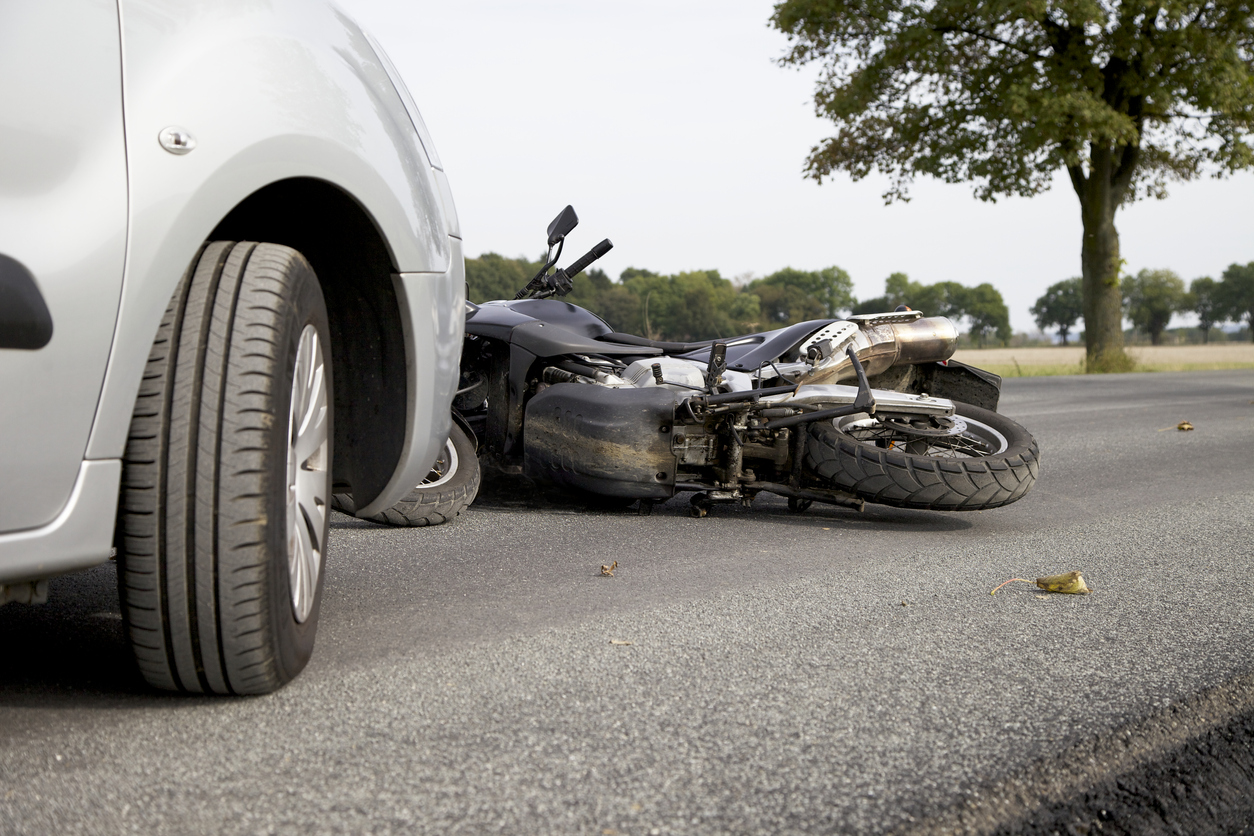 motorcycle on a road in front of a car after it was hit in an accident collision