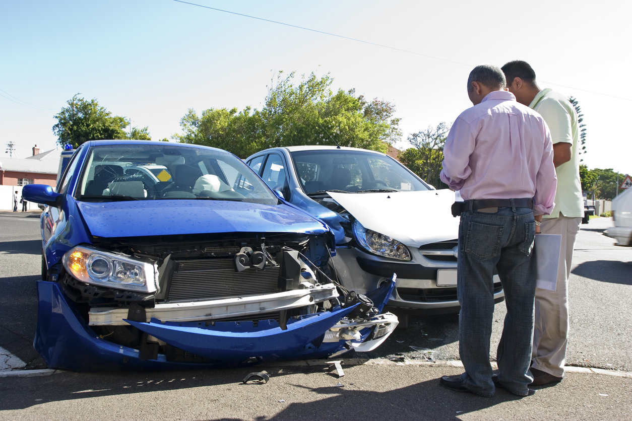 Two men next to two damaged cars after an accident